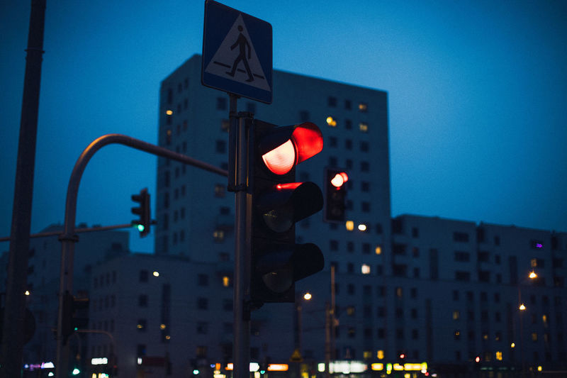 Low angle view of stoplight against building at dusk
