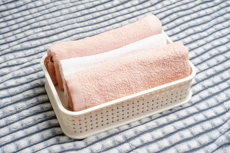 Plastic container with folded towels on a gray background, organizing space.