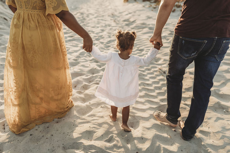 Behind view of young family walking at beach at sunset