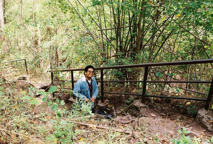 Full length of girl standing by railing in forest