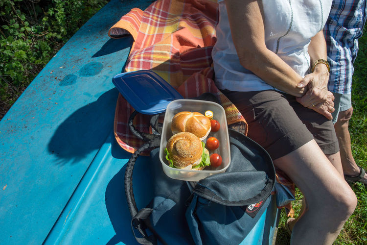 High angle view of senior couple with burgers in container sitting on upside down boat