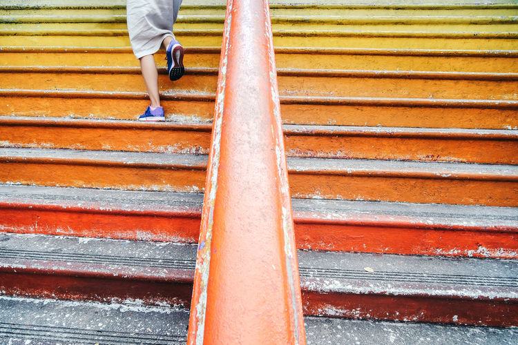 Low section of woman walking on orange staircase
