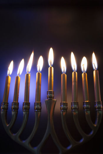 Hanukah candles lit in menorah against colorful background