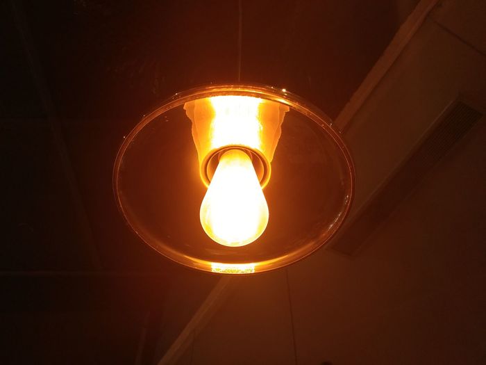 Low angle view of illuminated light bulb in the dark