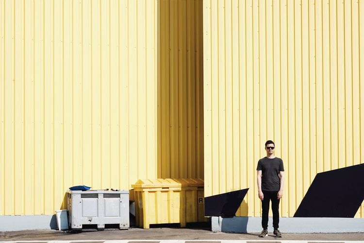 Full length of man standing against yellow cargo container