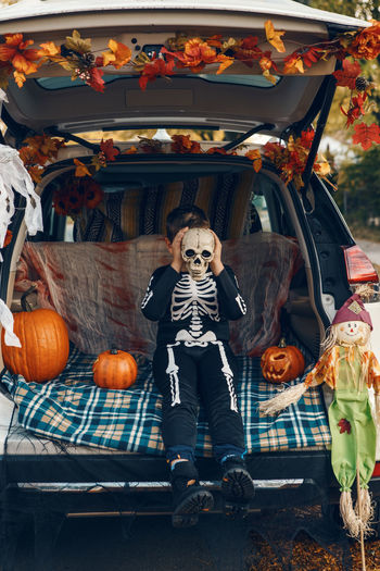 Cute kids wearing costume sitting in car trunk