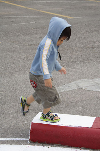 Boy wearing hooded shirt while walking on concrete block