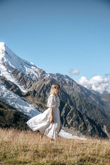 Woman standing on land against mountain and sky
