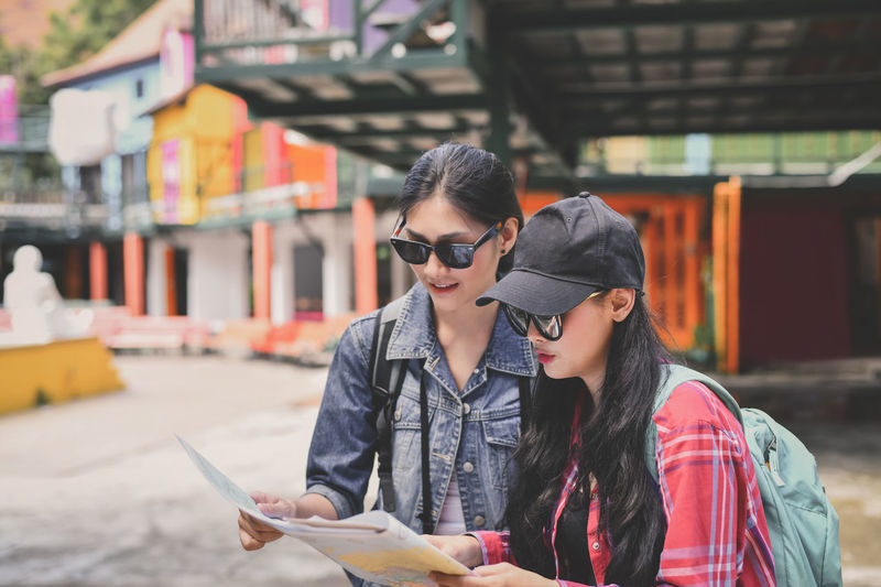Young woman with friend reading map