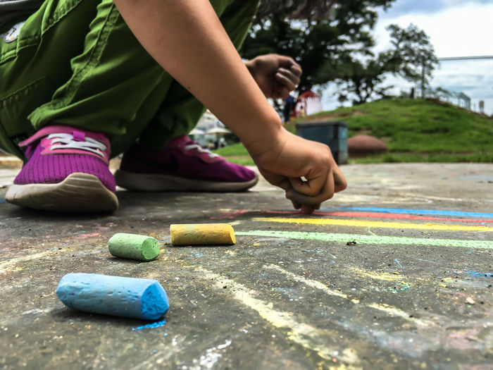 Low section of child drawing on asphalt