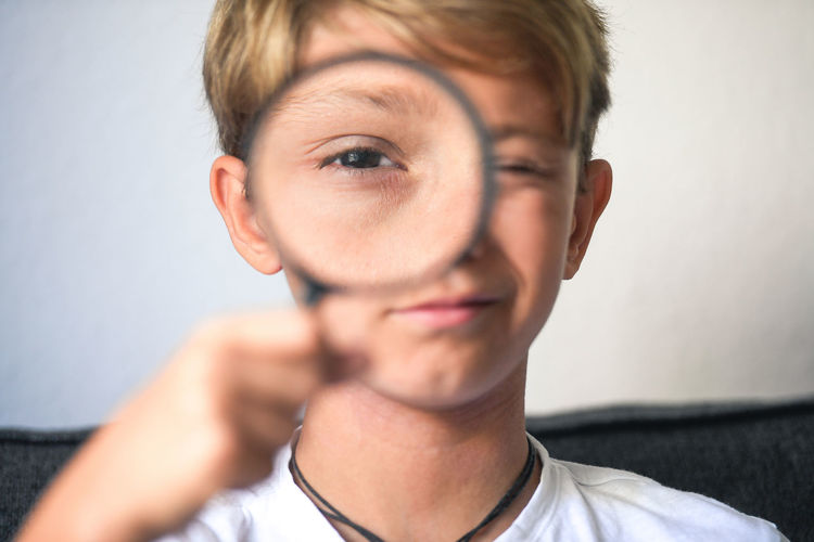 Boy holding magnifying glass at home 