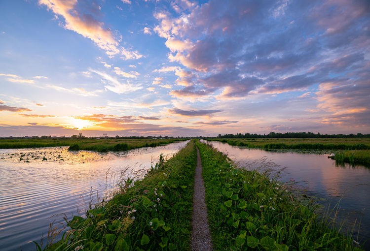Path over a dike in holland under colorful skies during sunset