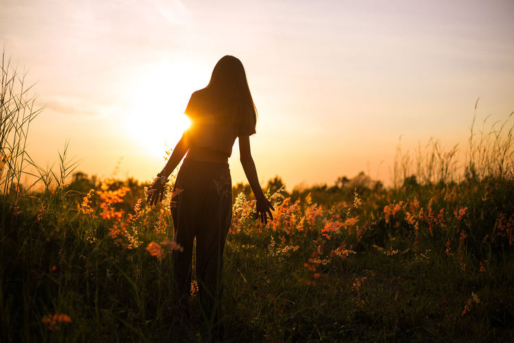 Silhouette person standing on field against sky during sunset