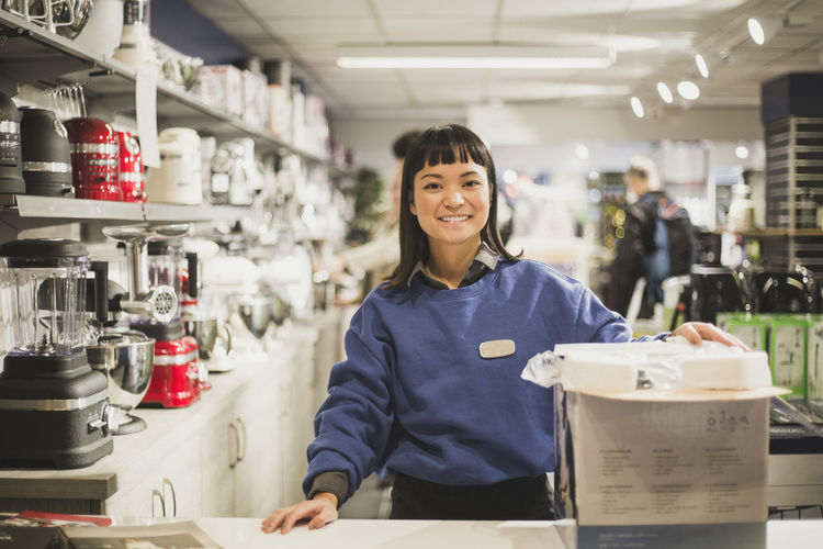 Portrait of smiling saleswoman with appliance standing in store