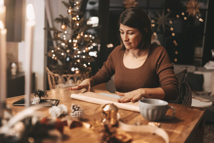 Good mood woman in a cozy environment wrapping gifts for christmas, stylish decoration, vintage