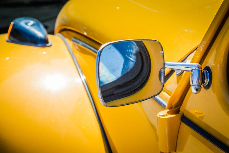 Close-up of yellow car on side-view mirror