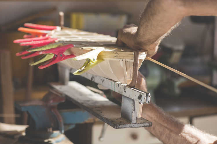 Close-up of man working on wooden boat model