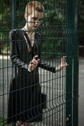 Young woman standing by fence