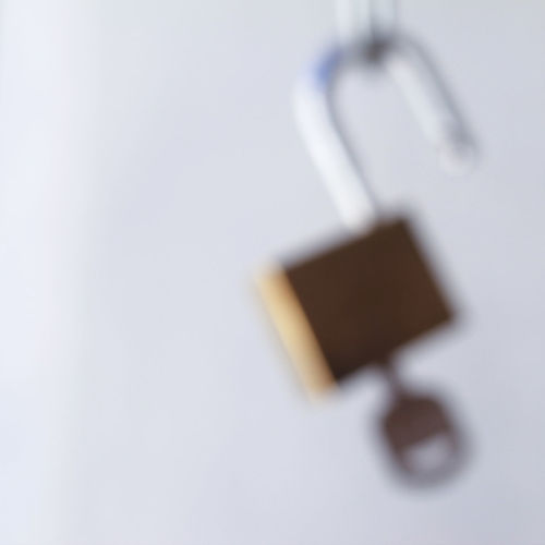 Close-up of padlocks hanging over white background