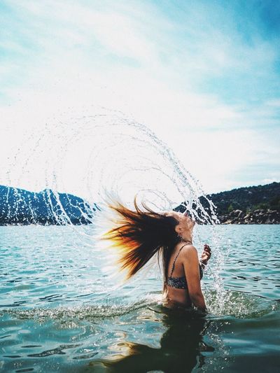 Full length of young woman in water against sky