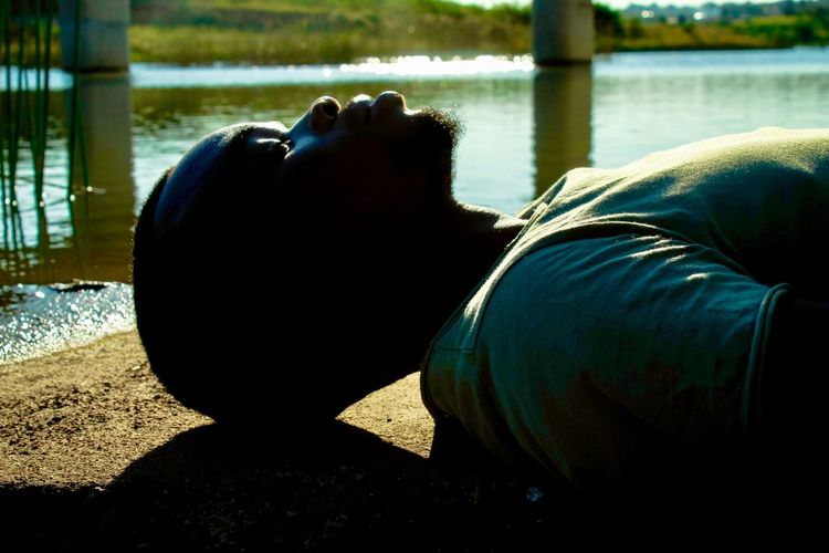Side view of man lying down by lake