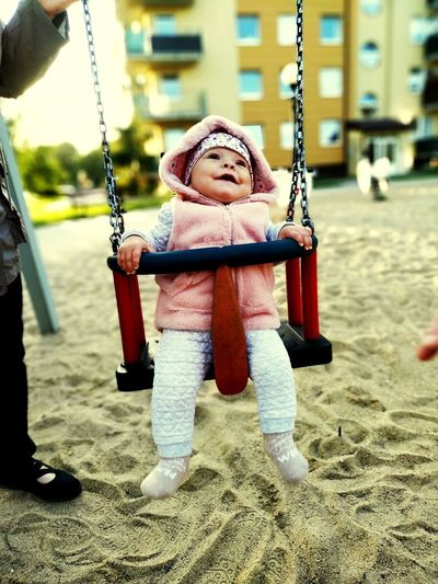 Full length of cute girl sitting at swing in playground