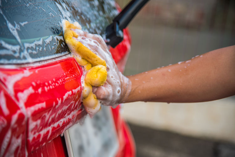Cropped hand of person washing car