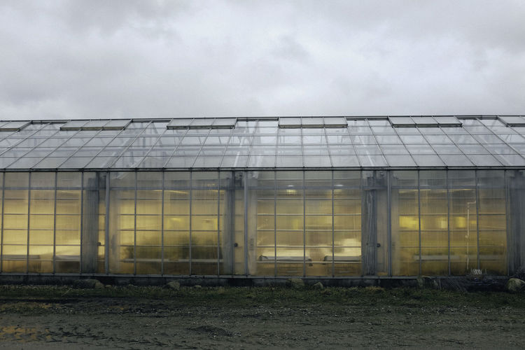 Low angle view of glasshouse against cloudy sky