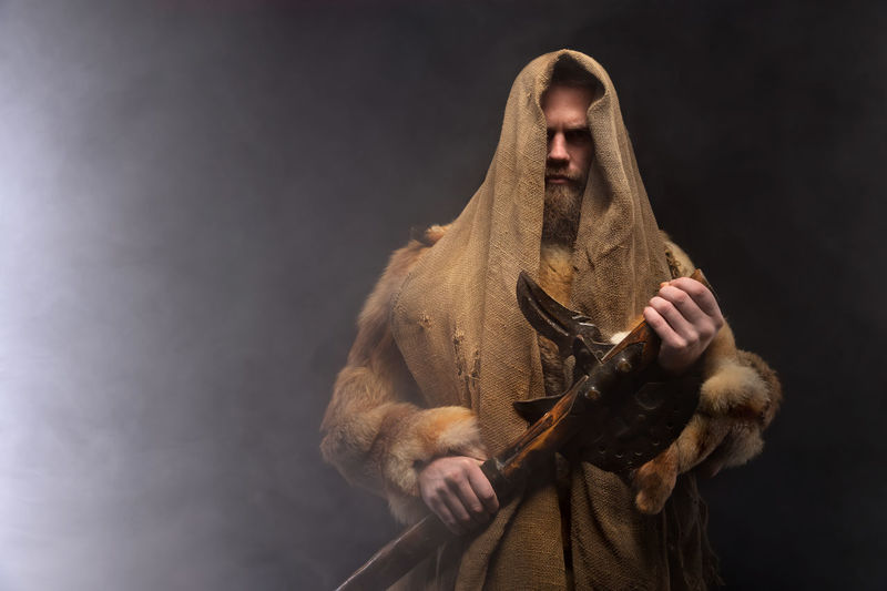 Midsection of man holding wooden axe against black background