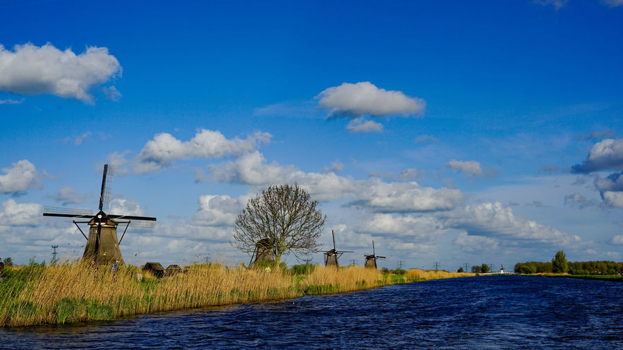 Traditional windmill on field against blue sky