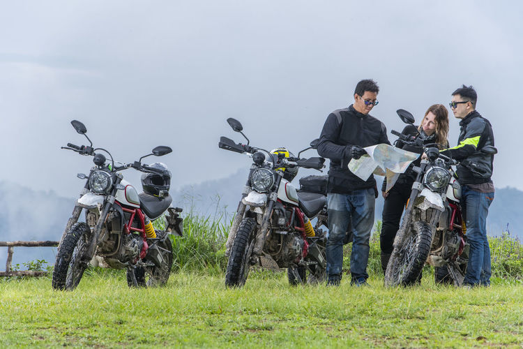 Three friends looking at map on motorcycle trip