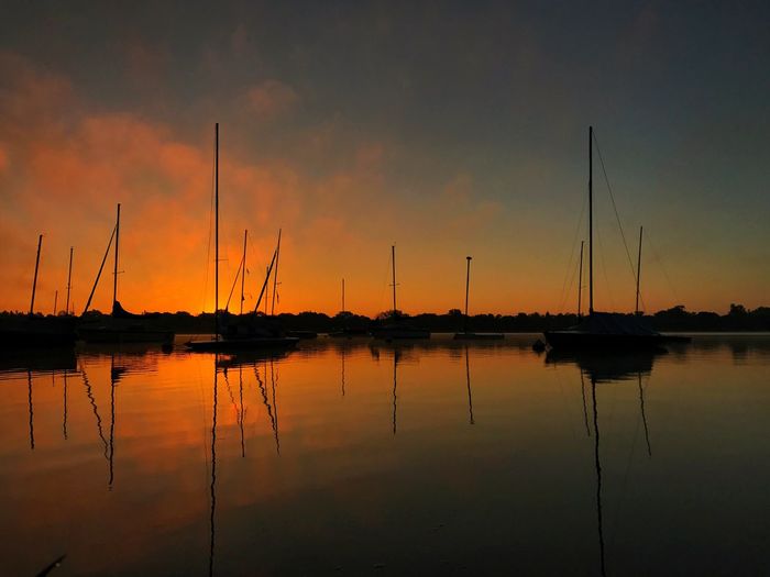 Sailboats in calm sea at sunset