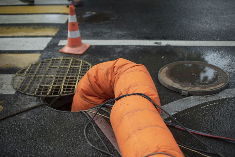 Orange pipe descends into hatch. sewer repair. wastewater pumping. air supply. sewer repair.