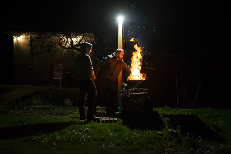 A father and son build a barbecue fire on their plot to cook dinner on an open fire. 