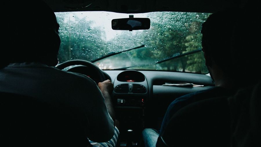 Man with friend driving car during rainy season