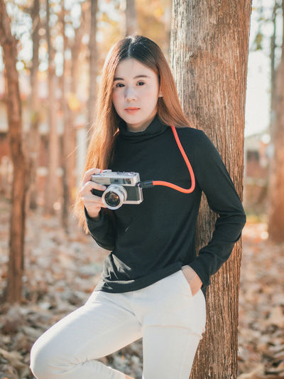 Portrait of woman with camera outdoors