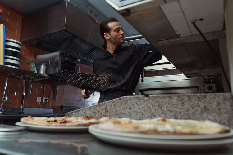 Male chef preparing italian pizza in restaurant kitchen