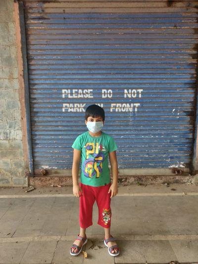 Full length of boy standing by text on wall