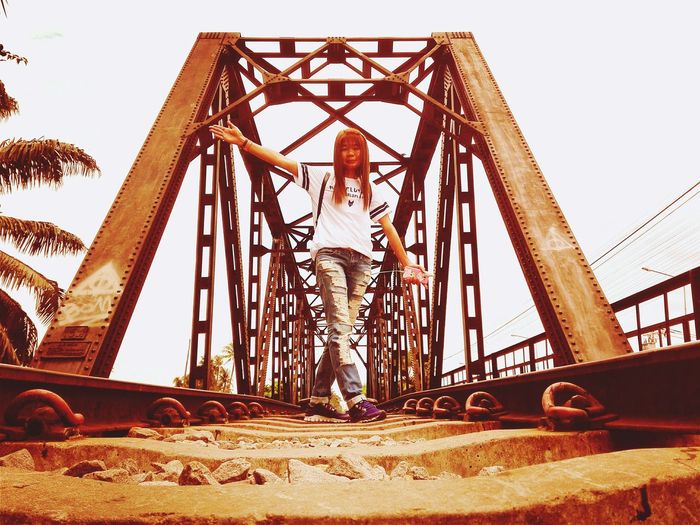 Low angle view of woman standing against bridge