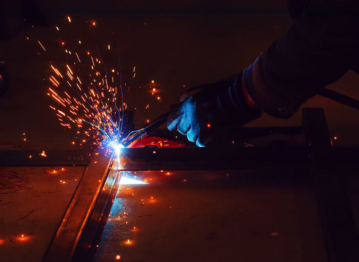 Tig welder with welding gloves is holding welding torch of a welding machine and welding steel