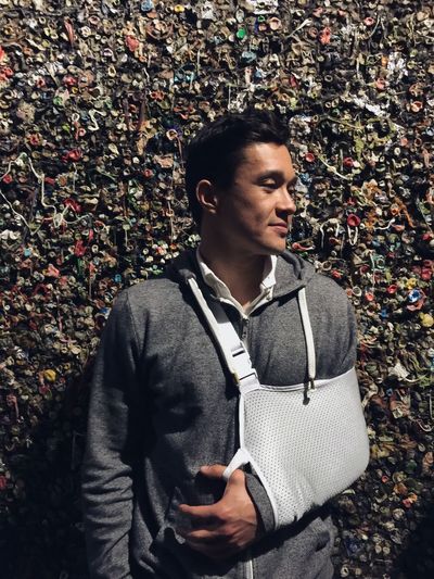 Man with fractured hand standing by gum wall