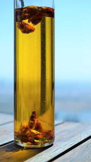 Close up view on bottle of gold olive oil with red paprika at wooden surface