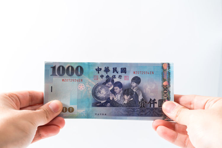 Cropped hand holding paper currency against white background