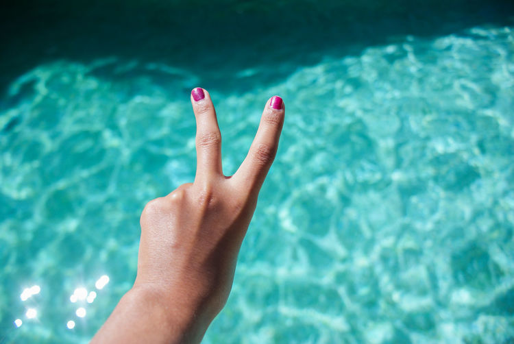 Woman showing peace sign over sea