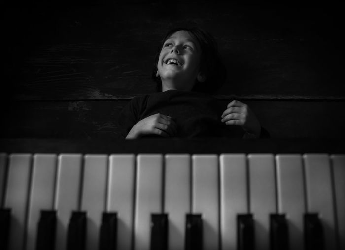 Portrait of smiling kid laying on the floor near piano