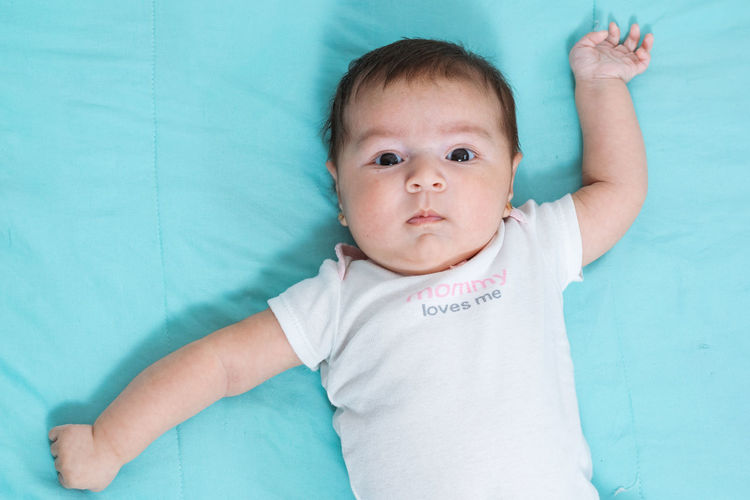 Medium shot of beautiful two months old latina baby lying on a blue sheet