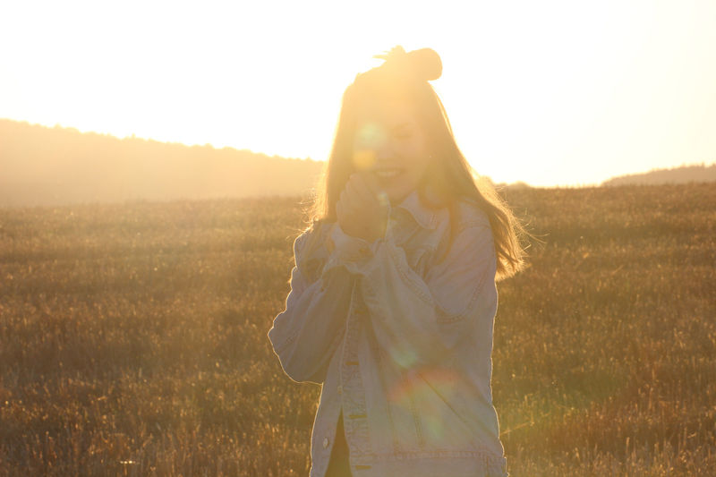 Portrait of young woman in field during sunset