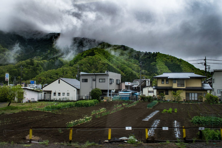 Houses on mountain against sky during rainy season