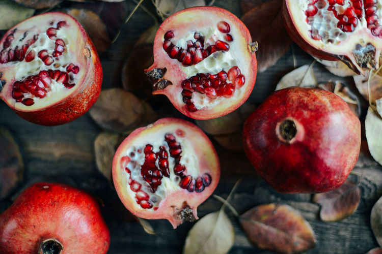 Close-up of pomegranate with autumn leaves on table