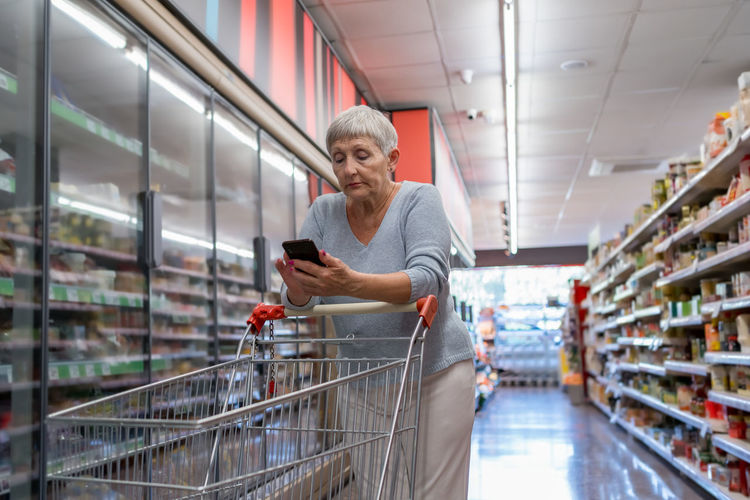 Caucasian elderly woman with white hair shopping in supermarket